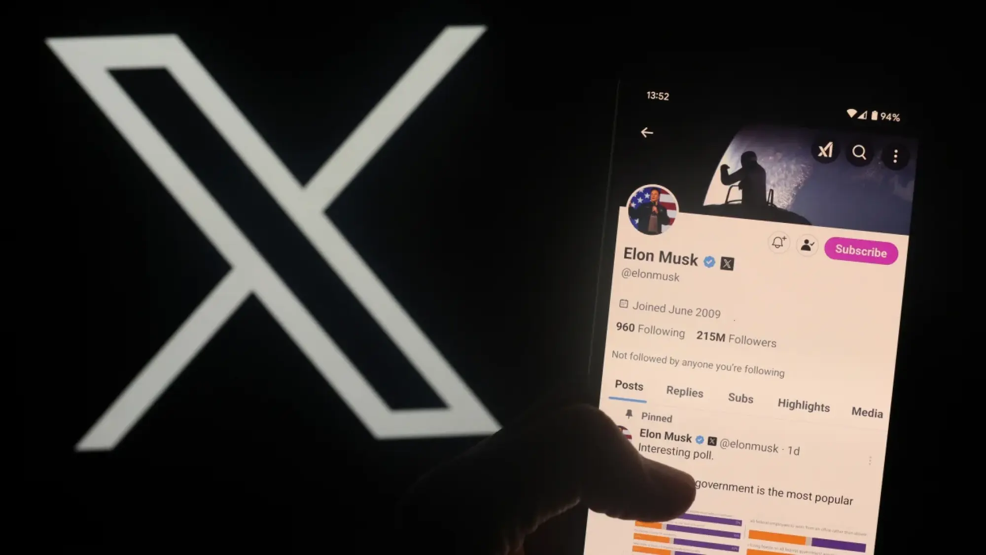 a user holds up phone showing elon musk